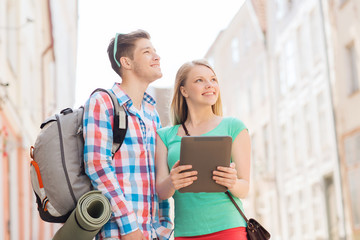 smiling couple with tablet pc and backpack in city