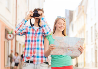 smiling couple with map and photo camera in city