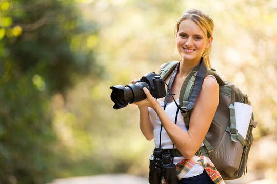 young woman holding a dslr camera in mountain