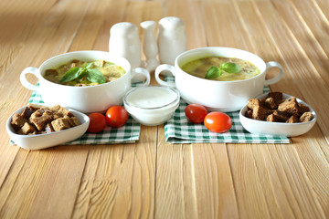Tasty soup in saucepans on wooden table, close up