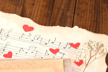 Dried rose flower on music book, close-up, on wooden background