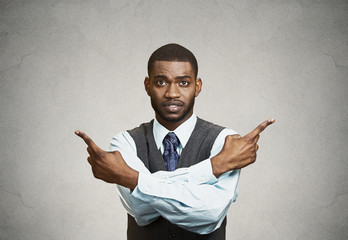Portrait confused man pointing in two different directions