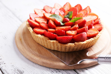 Strawberry tart on wooden tray, on color wooden background