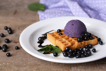 Tasty belgian waffles with ice cream on wooden table