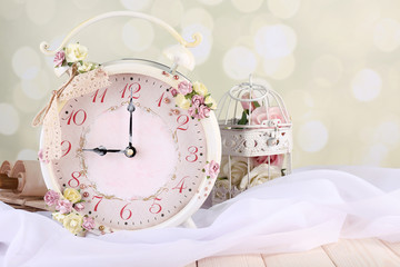 Beautiful vintage alarm clock with flowers on light background