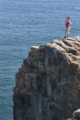 Fototapeta na wymiar Young woman at the top of a cliff overlooking the ocean