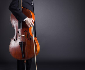 Cello musician standing with a dark background.