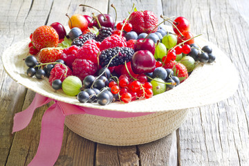 Summer wild berry fruits in the hat concept on vintage boards