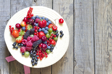 Summer wild berry fruits in the hat concept on vintage boards