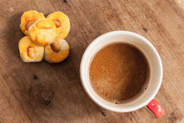 coffee cup with cookie on wood table.