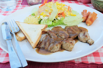 Pork steak with bread, sausage and salad