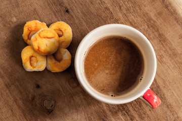 coffee cup with cookie on wood table.
