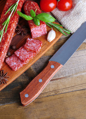 Tasty salami sausage and spices on wooden background