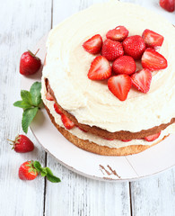 Delicious biscuit cake with strawberries on table close-up