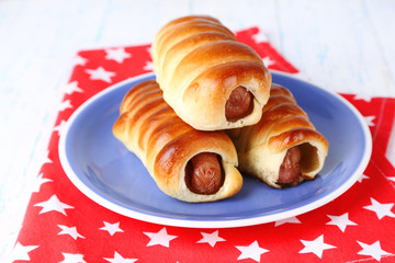 Baked sausage rolls on plate on table close-up
