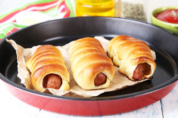 Baked sausage rolls in pan on table close-up