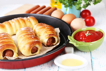 Baked sausage rolls in pan on table close-up