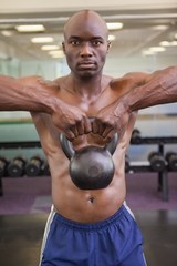 Obraz na płótnie Canvas Muscular man lifting kettle bell in gym