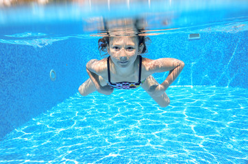 Active underwater child swims in pool, girl swimming