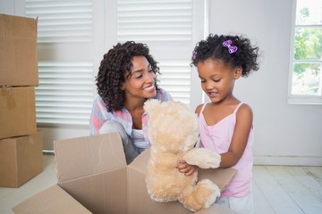 Cute daughter unpacking her teddy bear with mother