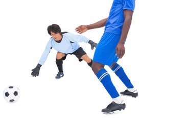 Fototapeta na wymiar Football player in blue striking at keeper
