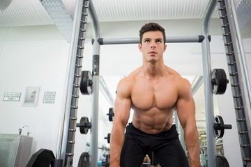 Fototapeta na wymiar Shirtless muscular man lifting barbell in gym