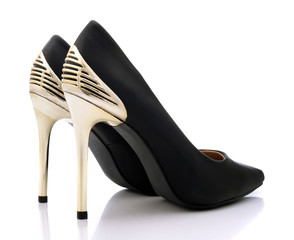 Sexy black shoes with high gold heels on white background