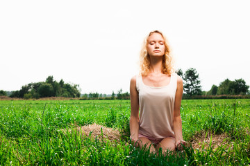 Beautiful woman meditating in summer park