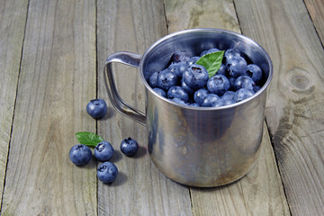 blueberries in metal cup on wooden background