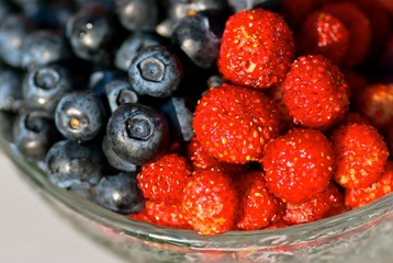 Glass bowl with blueberries and wild strawberries.