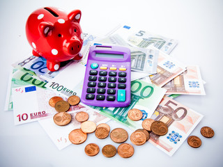 Red piggy bank with calculator and money.