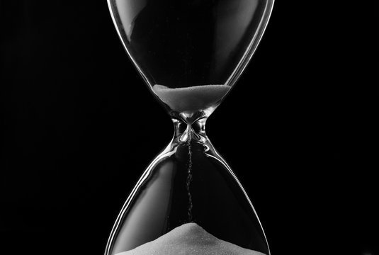 Sand trickling through the bulbs of an hourglass