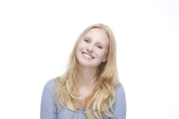 Junge blonde Frau lächelt gegen weisser Hintergrund