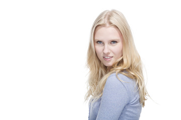 Junge blonde Frau lächelt gegen weisser Hintergrund
