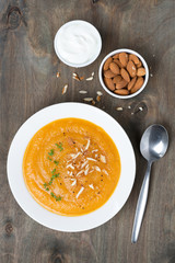carrot soup with almonds and yogurt on the plate, top view