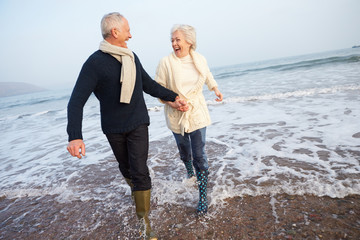 Senior Couple Walking Along Winter Beach