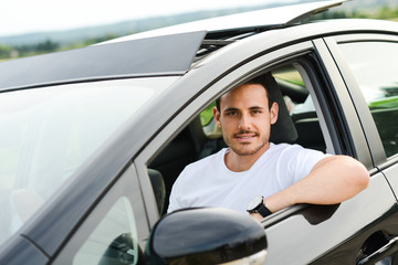 Fototapeta na wymiar handsome young man driving new car countryside summer vacation