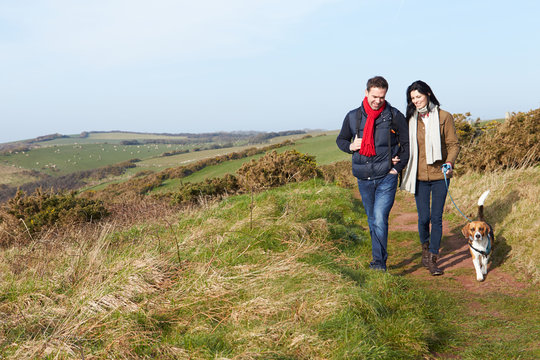 Couple With Dog Walking Along Coastal Path