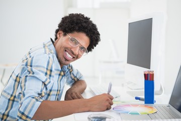 Fototapeta na wymiar Young designer working at his desk smiling at camera