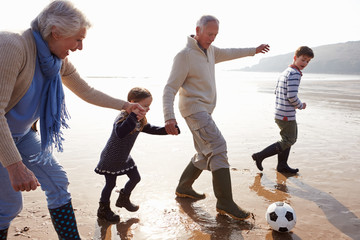 Grandparents With Grandchildren Playing Football On Beach