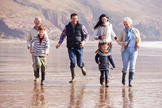 Multi Generation Family Running On Winter Beach