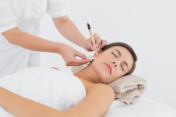 Obraz na płótnie Canvas Beautiful woman receiving ear candle treatment at spa center