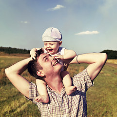 father holds a small child on his shoulders