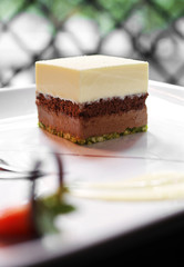 close up brownie and chocolate cream cake in white dish