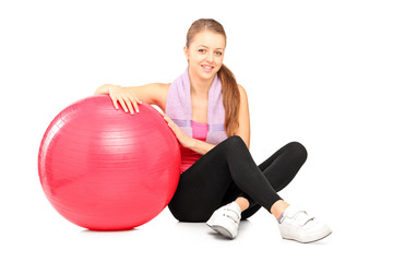 Young girl sitting next to a fitness ball