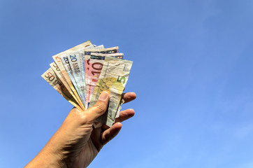 Euro Geldscheine in Hand vor blauem Himmel