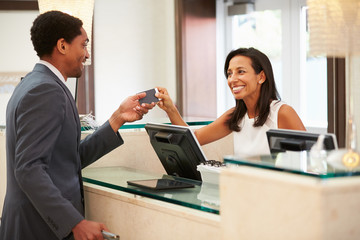 Businessman Checking In At Hotel Reception Front Desk