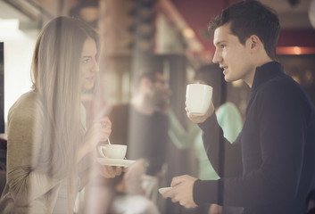 Two couples shot through window enjoying coffee