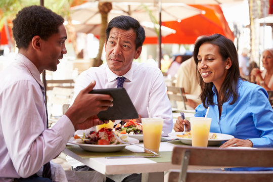 Three Businesspeople Having Meeting In Outdoor Restaurant