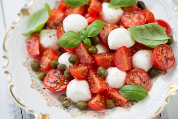 Close-up of caprese salad with capers and green basil leaves